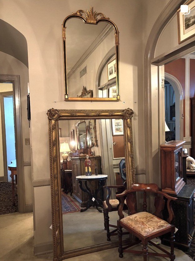 A corner of the Roush Antiques booth: a tall gilt floor mirror set in an archway, framed by antique furniture.