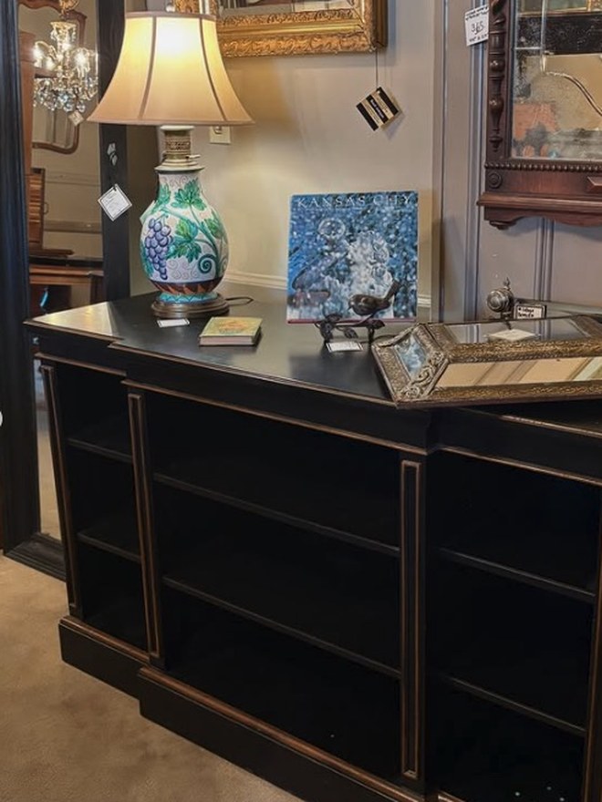 A long low ebonized bookcase styled with a lamp and framed art, the kind of accent used in home staging