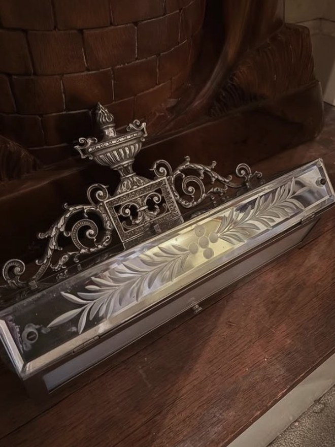 Victorian casket of beveled glass panels with wheel-cut fern etching and a silvered scrollwork gallery topped by an urn finial.