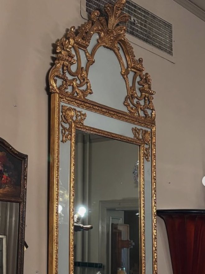 Tall narrow giltwood pier mirror with a pierced crest of scrolls and a plume spray, applied gilt ornament at the corners, and narrow mirrored border panels flanking the main plate.