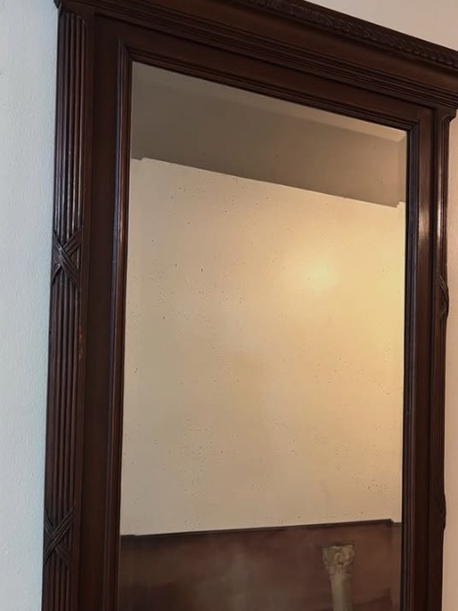 Tall neoclassical walnut mirror with a dentil-carved cornice, reeded frame, and carved rosette corner blocks.