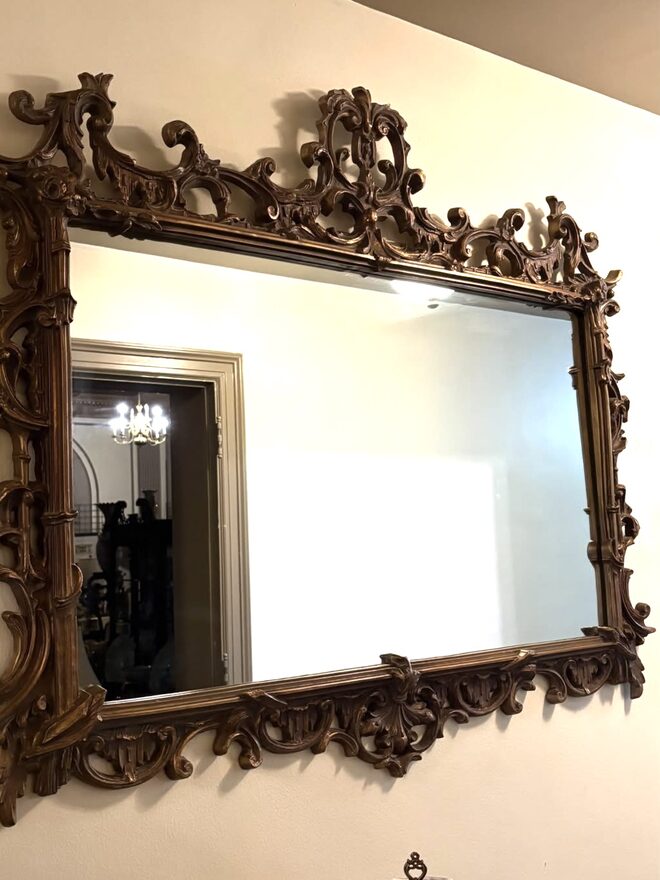 Large landscape wall mirror in a dark gilt frame carved with pierced C-scrolls and leafy rocaille across the top and bottom, with bamboo-carved stiles at the sides.
