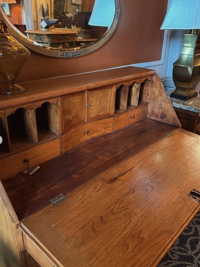 Slant-front bureau desk with the writing surface dropped open, revealing a fitted interior of pigeonholes and small drawers.